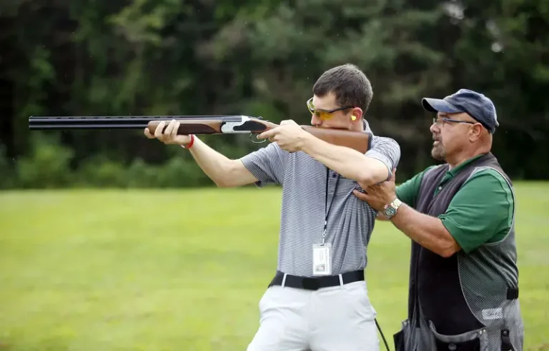 Two beginners shooting an air rifle in a field.