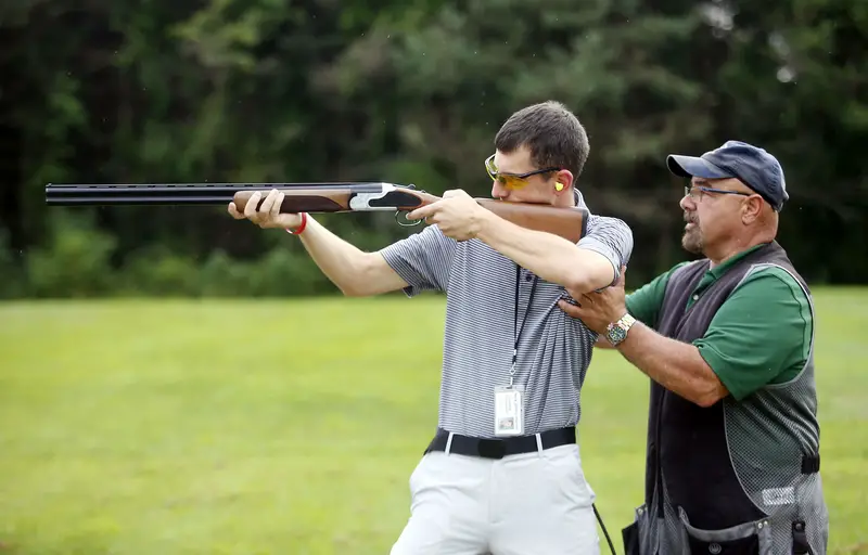 Two beginners shooting an air rifle in a field.